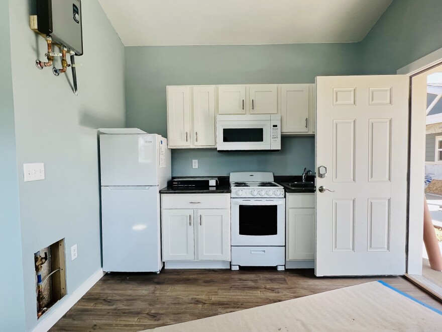 Interior of a tiny home at Veterans Community Project in Longmont showing a bed, desk area, and natural light from a window