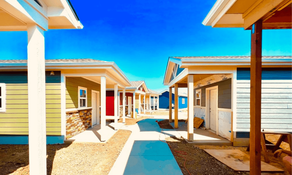 A sidewalk running through the Veterans Community Project tiny home village in Longmont, Colorado, with small homes on either side